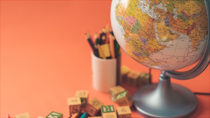 Globus, Stifte und Bauklötze auf orangenem Hintergrund